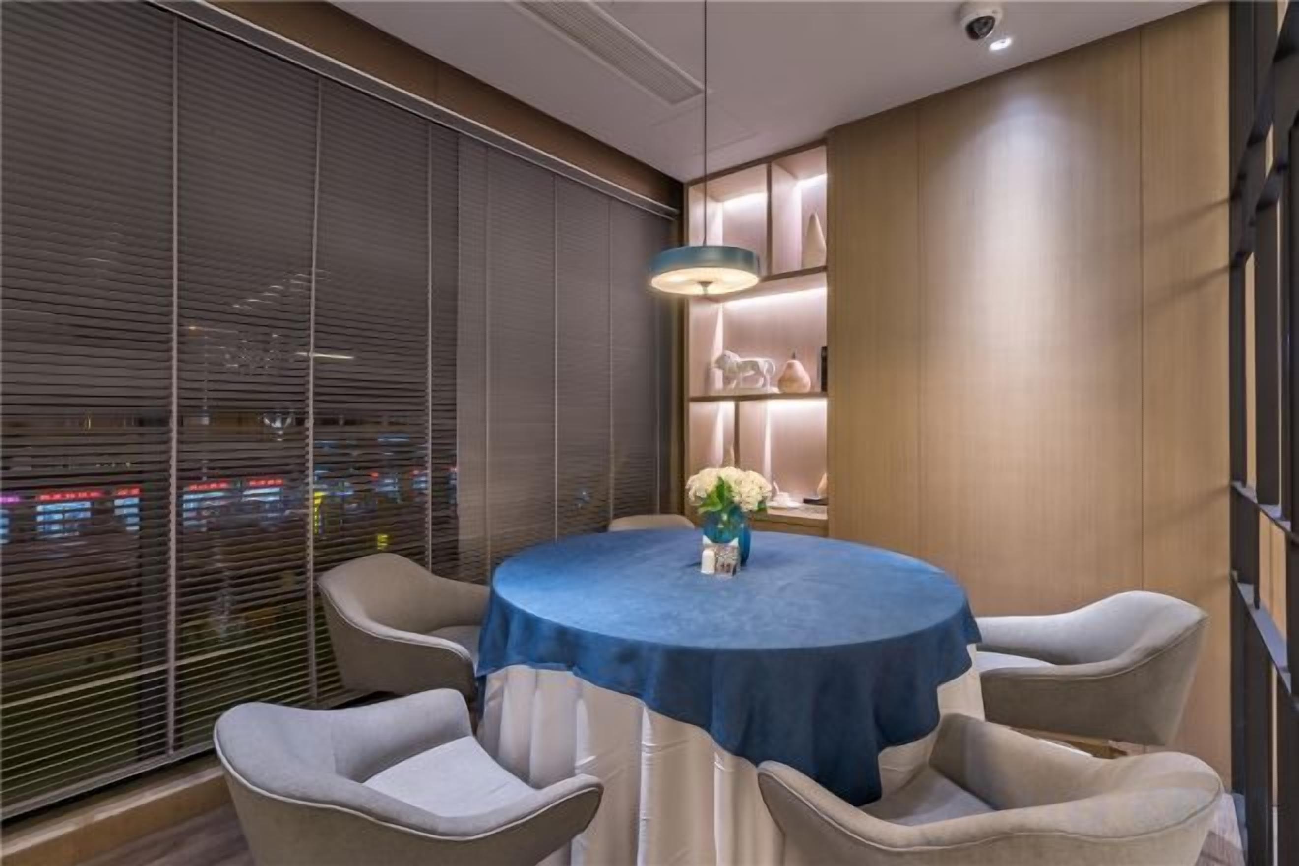 Un comedor con una mesa redonda, sillas y un florero.
