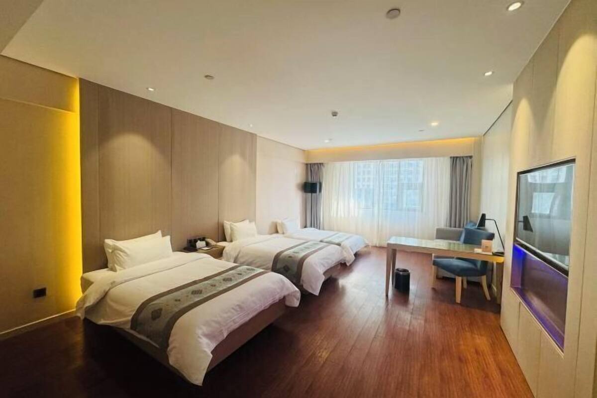 Une chambre d’hôtel avec deux lits, un bureau, une chaise et un téléviseur.