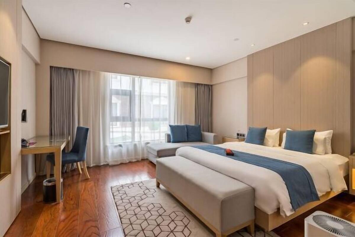 Une chambre d’hôtel moderne équipée d’un grand lit, d’un bureau, d’une chaise et d’un téléviseur.