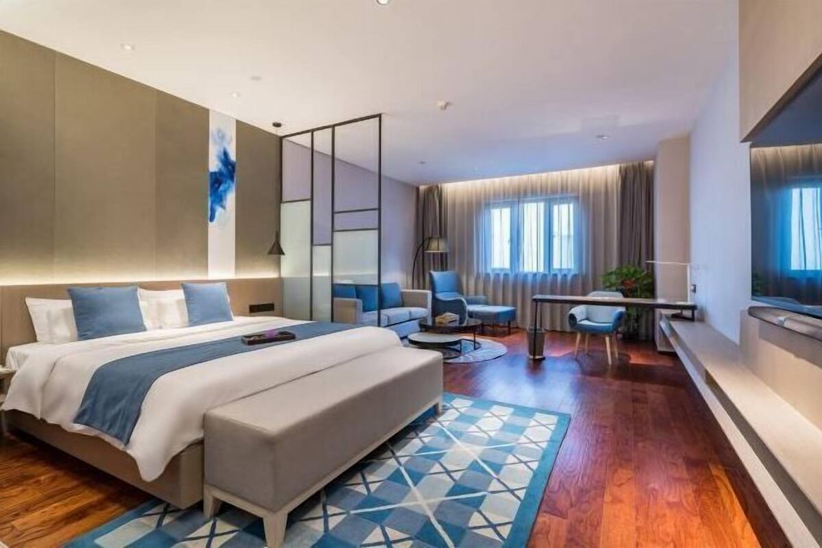 Une chambre d’hôtel moderne avec un grand lit, un coin salon avec une table basse et un téléviseur.