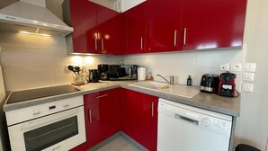 A kitchen with red cabinets, a white dishwasher, and a stove. - Modern and Bright home walk to beach with garage (Berck-Plage)