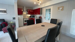 A modern kitchen with red cabinets, a dining table with chairs, and a ceiling light fixture. - Modern and Bright home walk to beach with garage (Berck-Plage)