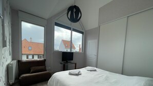 A bedroom with a bed, a TV on a stand, a window, and a radiator. - Modern and Bright home walk to beach with garage (Berck-Plage)