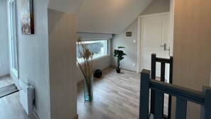 A modern interior with a sloped ceiling, a wooden staircase, a radiator, a window, and a potted plant. - Modern and Bright home walk to beach with garage (Berck-Plage)