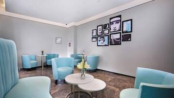 Uma área de espera moderna com cadeiras azul-claras e uma pequena mesa com um vaso de flores.