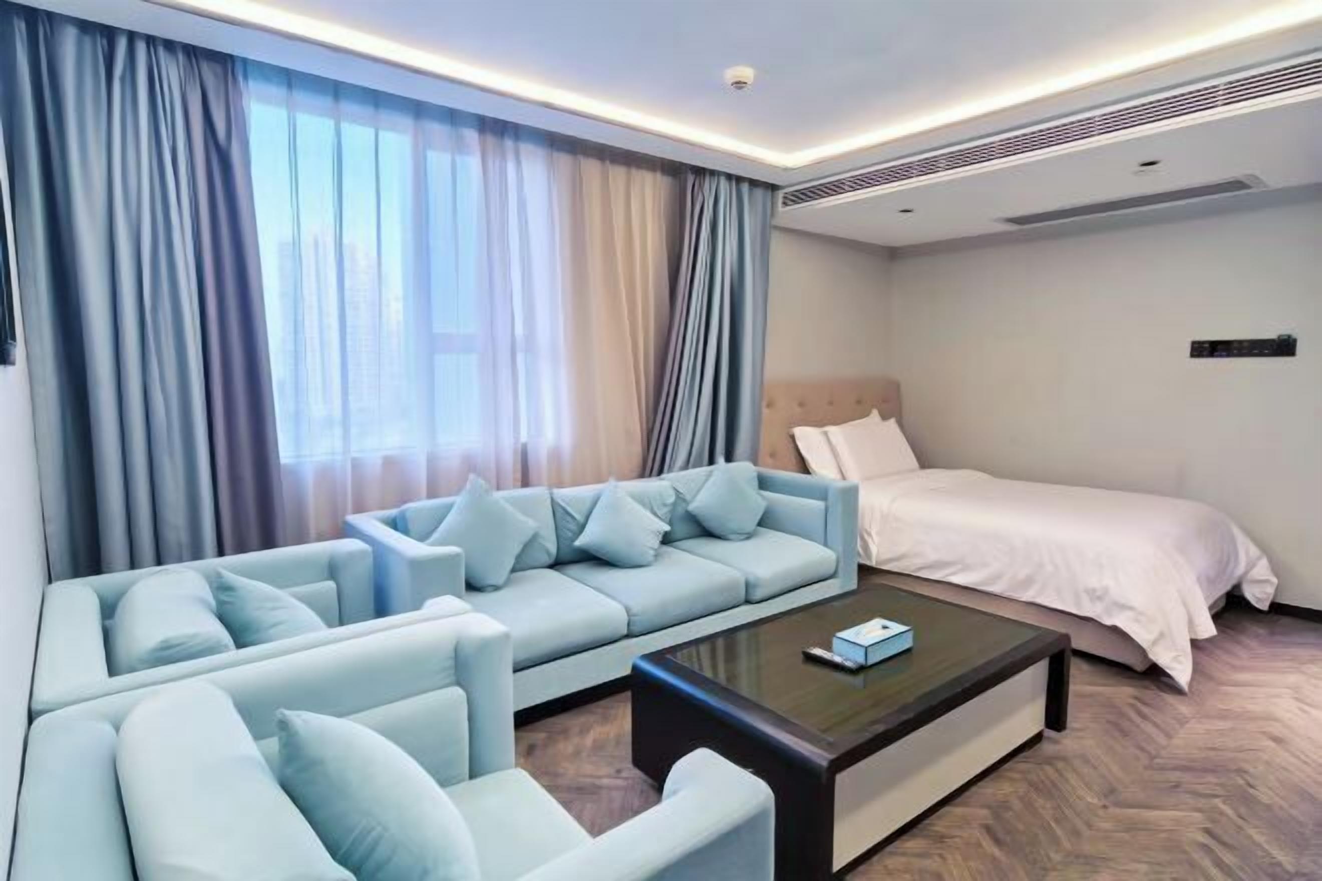 Una habitación de hotel moderna con un sofá azul claro, una cama y una mesa de centro.