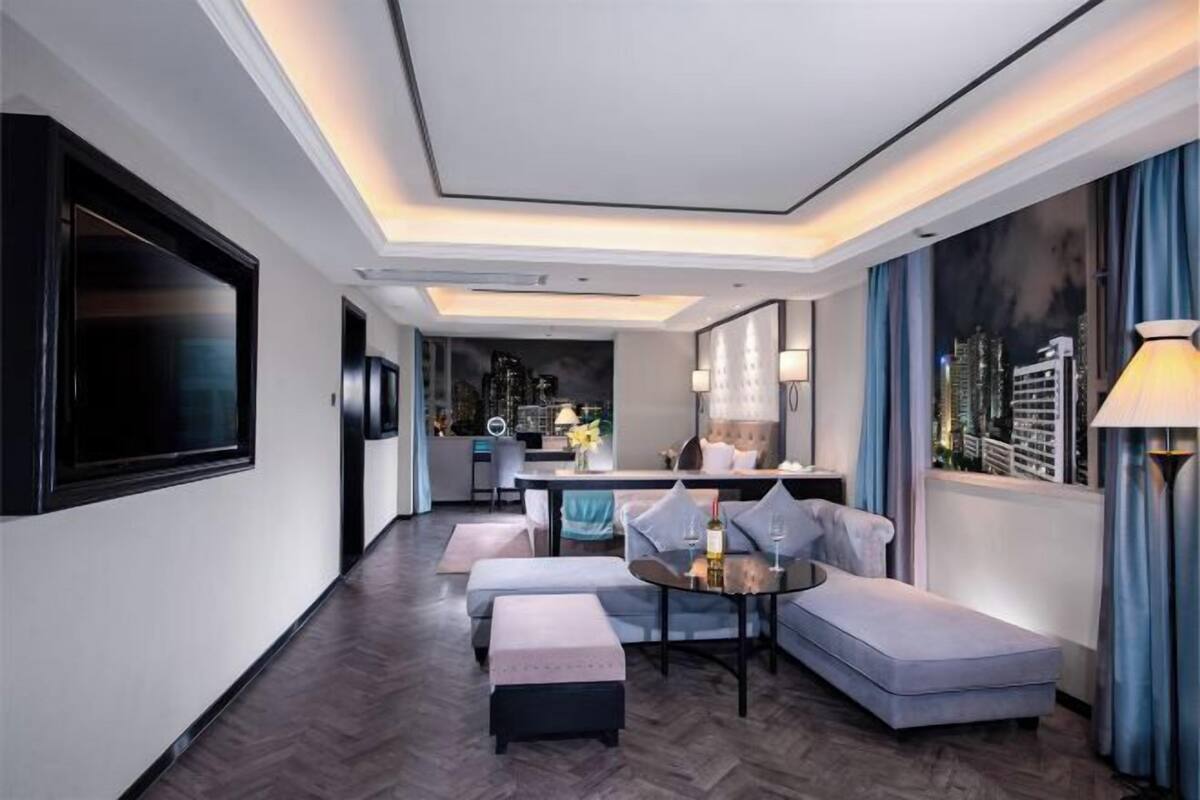 Una habitación de hotel moderna con comedor, un conjunto de sofás y vistas a la ciudad.