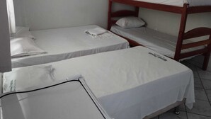 Una camera del dormitorio con letti a castello e un letto singolo, il tutto con biancheria da letto bianca.