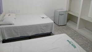 Una stanza piccola e pulita con un letto singolo, una scrivania e un frigorifero compatto.