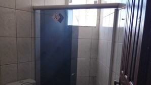 Un piccolo box doccia chiuso con il water a sinistra.