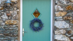 A teal door with a wreath, set in a stone wall.