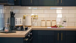 A modern kitchen with dark cabinets, a countertop with a toaster, kettle, and jars, and a dining area with a table set for breakfast.