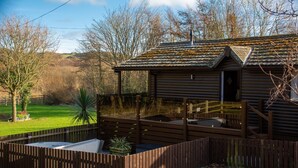 Een houten blokhut met een schuin dak, een veranda en een omheinde tuin.