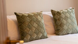 Een opgemaakt bed met twee groene kussens en een witte deken.