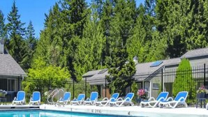 A pool area with lounge chairs and a building with a sloped roof.