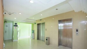 A clean, modern lobby with two elevators, a water dispenser, and a trash bin. - Rulai Hotel (Shanghai)