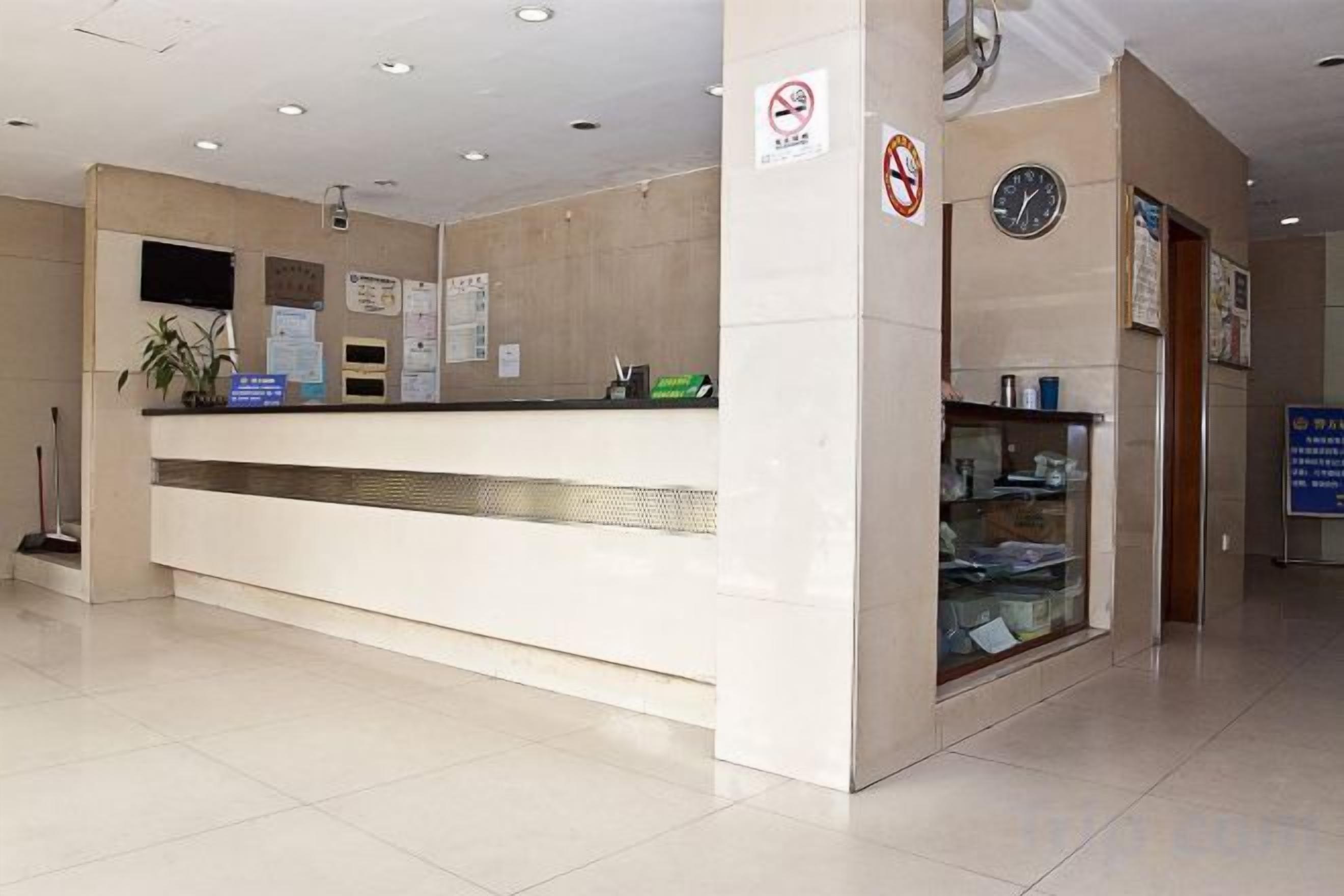 Una mesa de recepción con un reloj, un cartel de prohibido fumar y una vitrina de vidrio.