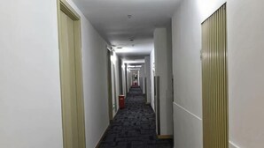 A long, narrow hotel corridor with carpeted floors, white walls, and doors on both sides. - Rulai Hotel (Shanghai)