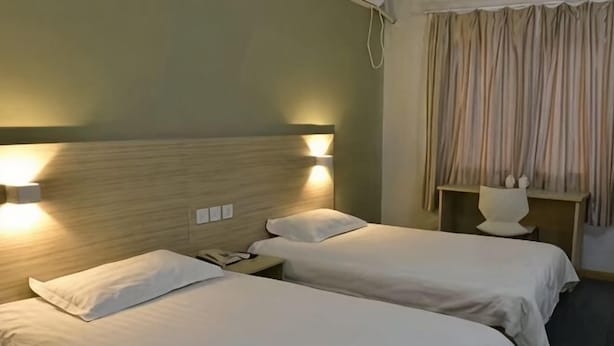 A hotel room with two beds, bedside lamps, a nightstand, and a curtain. - Rulai Hotel (Shanghai)