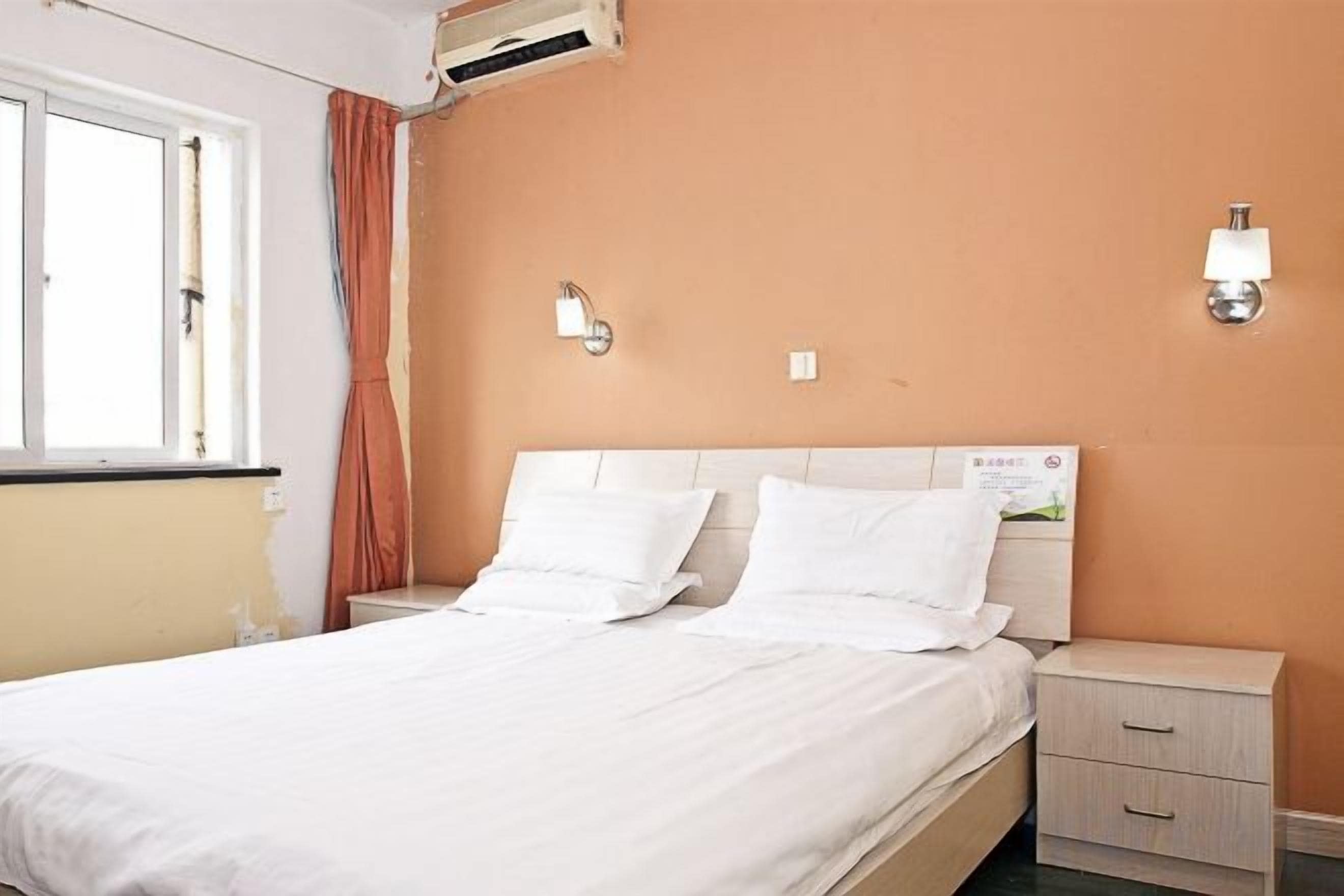 Una habitación de hotel con una cama, mesitas de noche y un aplique de pared.