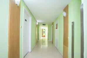 A hallway with doors on both sides, a light-colored floor, and a ceiling with recessed lighting. - Rulai Hotel (Shanghai)