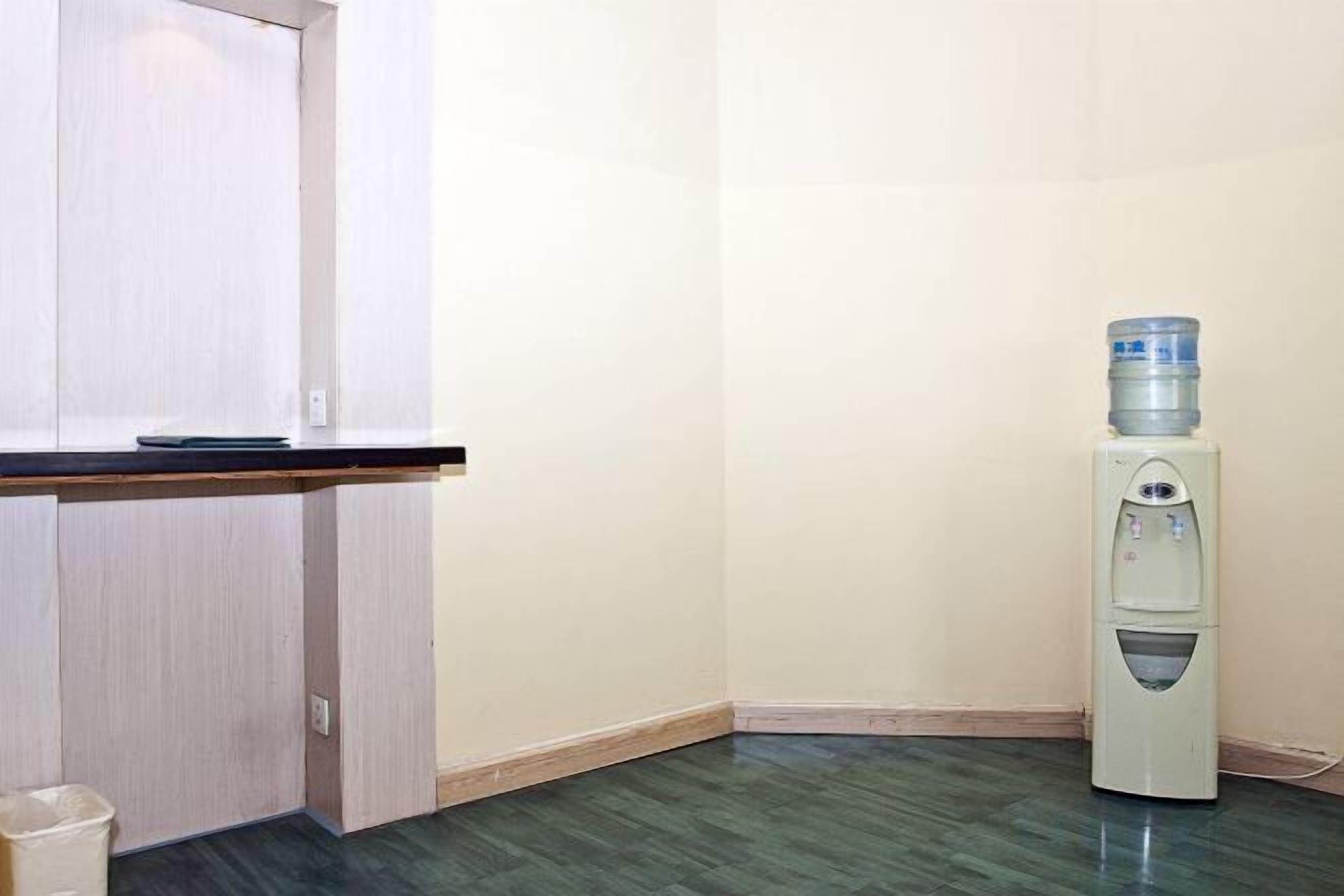 Una esquina de una habitación con un dispensador de agua, una puerta y un cubo de basura.
