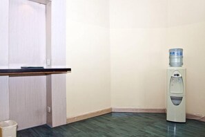 Una esquina de una habitación con un dispensador de agua, una puerta y un cubo de basura.