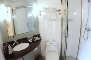 A bathroom with a sink, toilet, mirror, and shower. - Rulai Hotel (Shanghai)