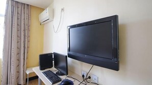 A room with a desk, a laptop, a monitor, and an air conditioner on the wall. - Rulai Hotel (Shanghai)