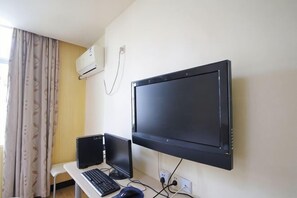 A room with a desk, a laptop, a monitor, and an air conditioner on the wall. - Rulai Hotel (Shanghai)