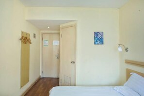 Une chambre d’hôtel avec un lit, une porte, un luminaire et une œuvre d’art accrochée au mur.