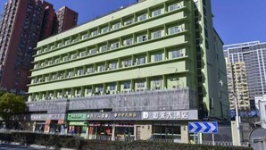 A multi-story hotel with a green facade, multiple balconies, and several ground-level shops. - Rulai Hotel (Shanghai)