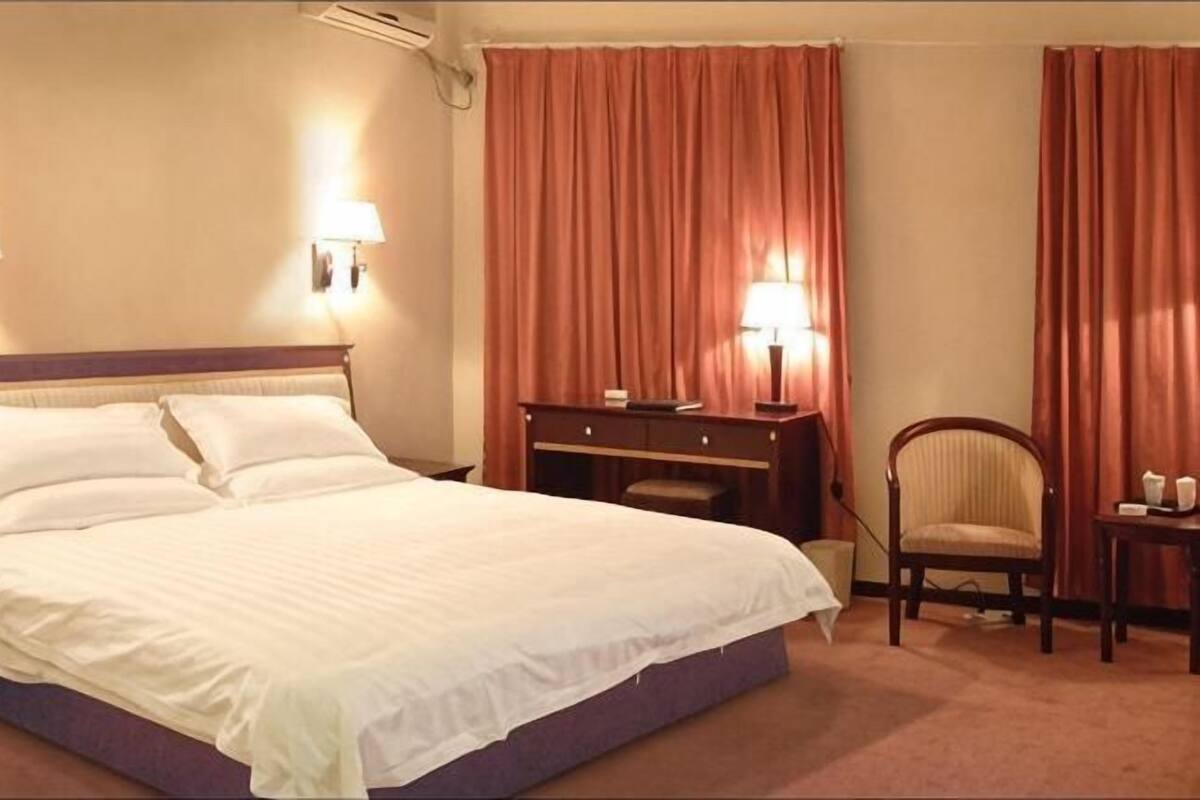 Habitación de hotel con cama, escritorio, silla y cortinas.