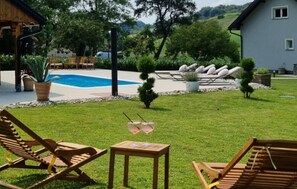 A pool area with lounge chairs, a table, and a small garden with potted plants. - Amazing home in Druzilovec with sauna (Druzilovec)