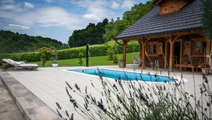 A pool area with lounge chairs, a wooden cabin, and a landscaped garden. - Amazing home in Druzilovec with sauna (Druzilovec)