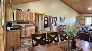 Una cocina acogedora con armarios de madera, una mesa de comedor y una sala de estar con un sofá y una planta en maceta.