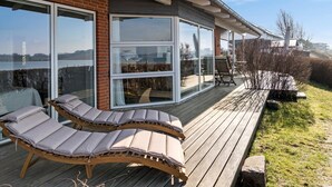 A modern house with a deck featuring two lounge chairs and a view of the water. - 3 bedroom gorgeous home in Hejls (Hejls)