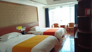 A hotel room with two beds, a wooden floor, a desk, and a chair.