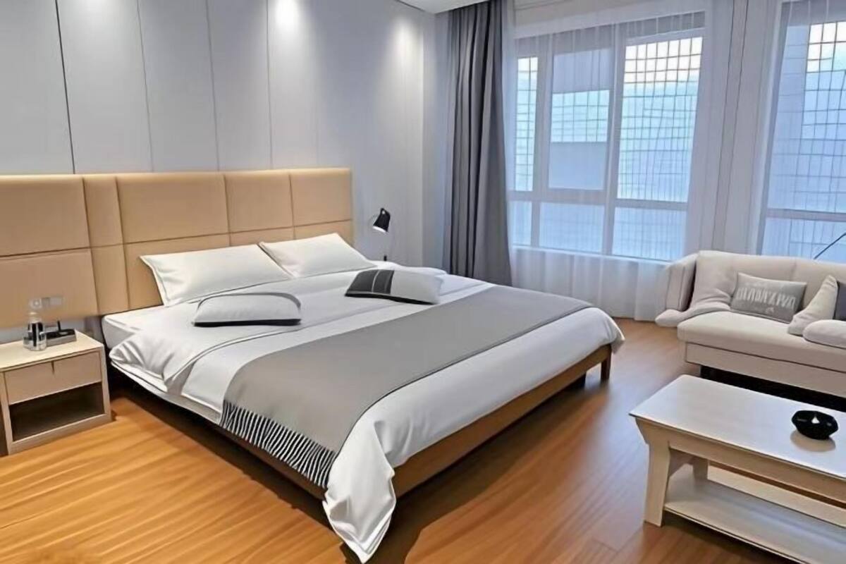 Una habitación de hotel moderna con una cama grande, una mesita de noche, un sofá y una mesa de centro.