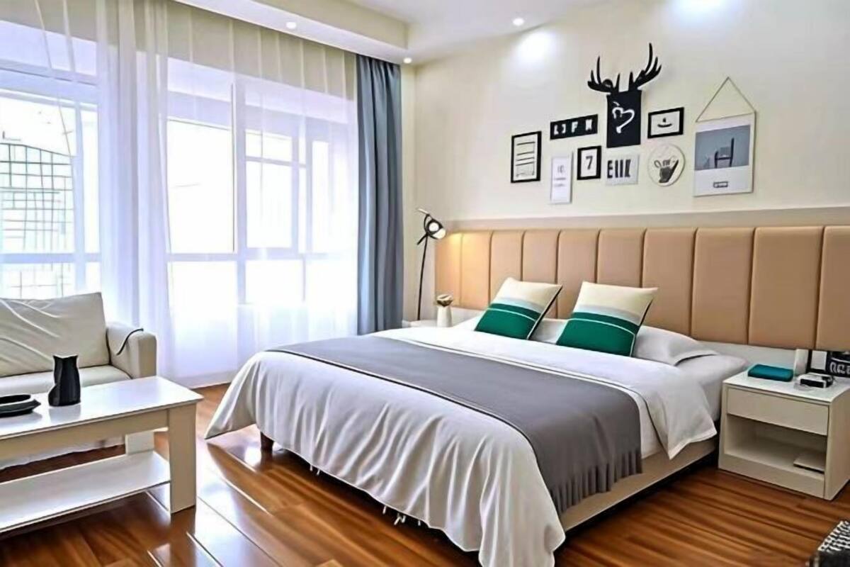 Una habitación de hotel moderna con una cama grande, mesitas de noche, un escritorio y una ventana con cortinas.