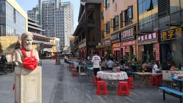 A street with outdoor seating, buildings with signage, and a statue.