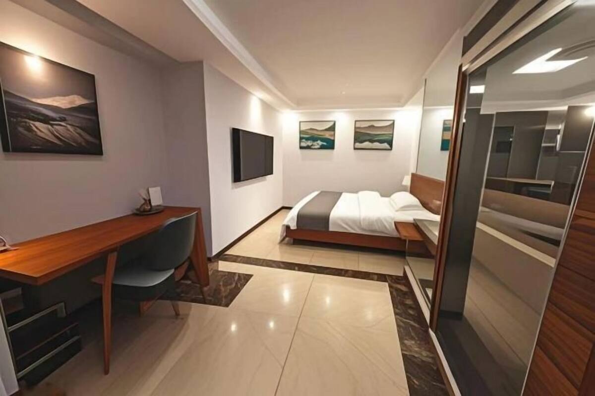Una habitación de hotel moderna con cama, escritorio y televisión.