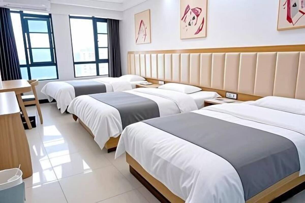 Una habitación de hotel con dos camas, un escritorio y una ventana.