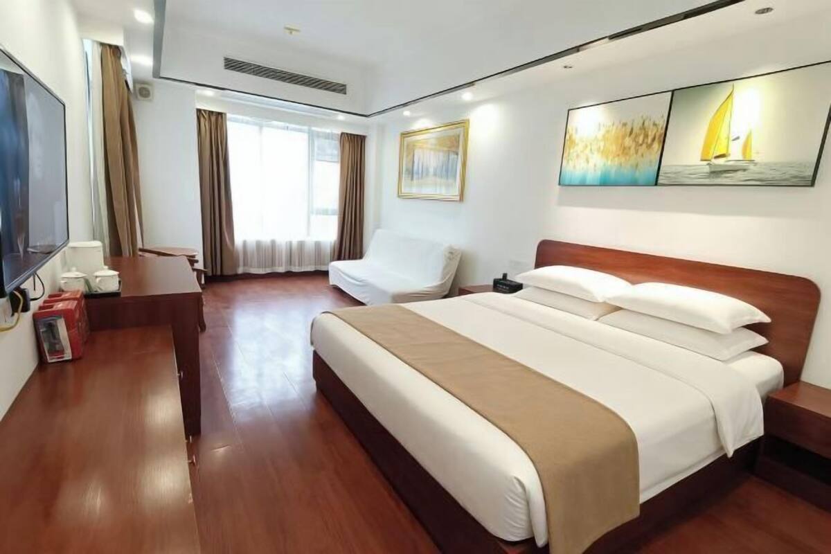 Habitación de hotel con una cama grande, un escritorio con silla, televisión y cuadros en la pared.