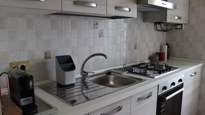 A modern kitchen with a stainless steel sink, a built-in stove, and a coffee maker. - Domus Marisa - Panoramic apartment in Naples area Posillipo/Mergellina (Napoli)