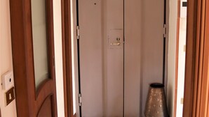 A hallway with a wooden door, a white door, and a tiled floor. - Domus Marisa - Panoramic apartment in Naples area Posillipo/Mergellina (Napoli)