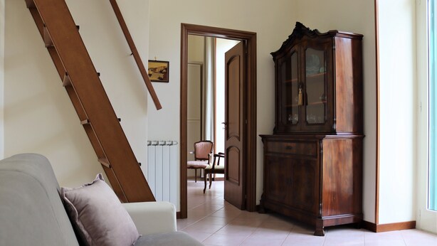 A room with a sofa, a wooden cabinet, and a staircase. - Domus Marisa - Panoramic apartment in Naples area Posillipo/Mergellina (Napoli)