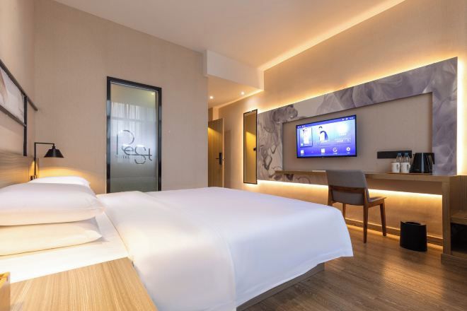 Ein modernes Hotelzimmer mit einem großen Bett, einem Schreibtisch mit Computer und einem Fernseher.