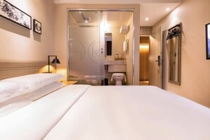 A hotel room with a large bed, a bedside table, a lamp, and a view into the bathroom. - Rest Comfort Hotel(Shanghai North Bund Ningguo Road Subway Station) (Shanghai)