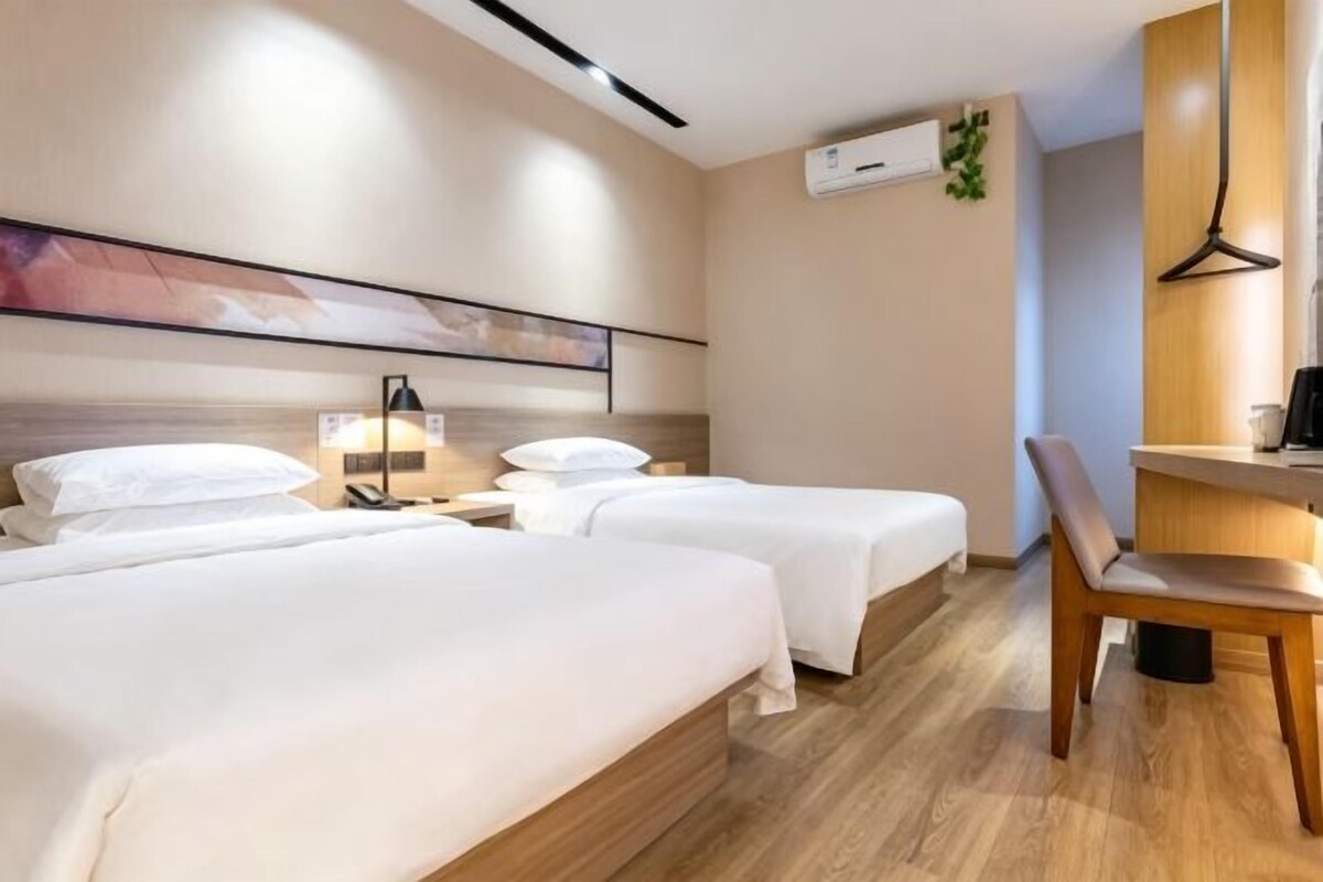 A hotel room with two beds, a desk, and a chair.